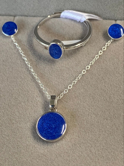 Sterling Silver jewelry set featuring a necklace, bracelet, and earrings with vibrant blue glittery circular stones made with resin and memorial ashes, displayed on a textured gray background.